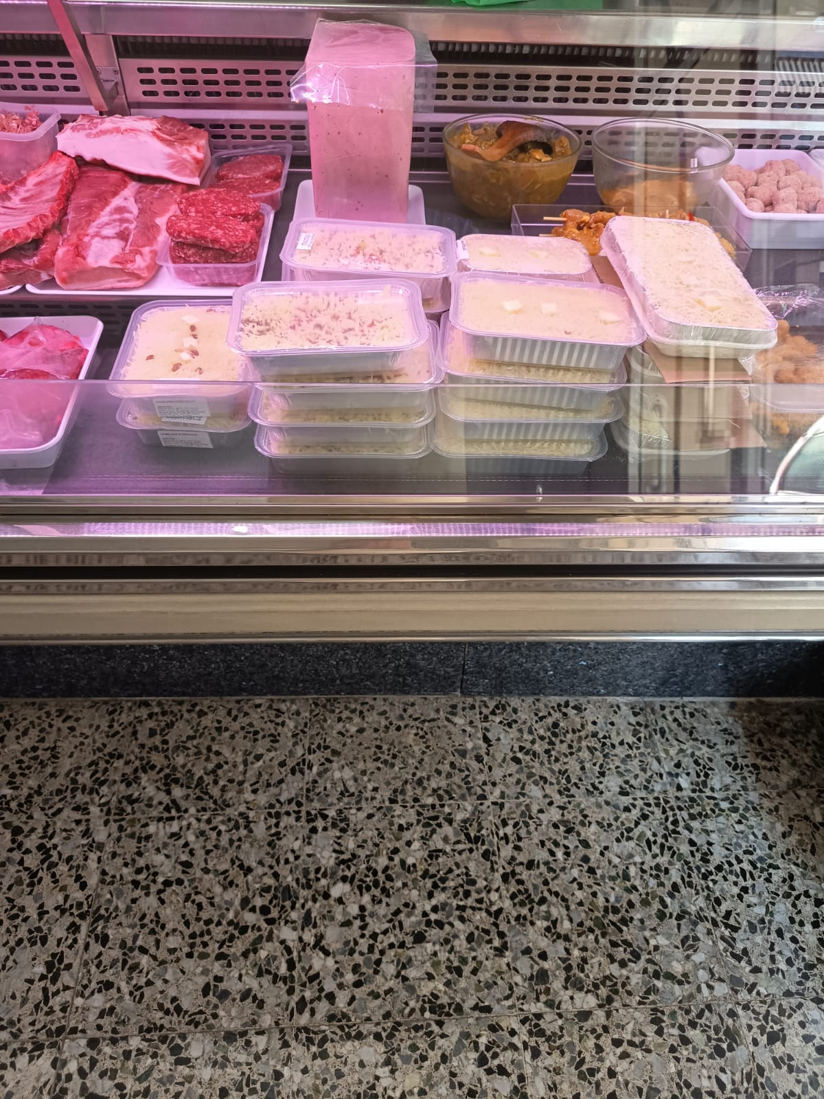 Vitrina refrigerada con bandejas de carne y embutidos variados en carnicería